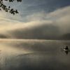 Paddler auf dem Gobenowsee am Morgen zwischen Sonne und Regenfront.